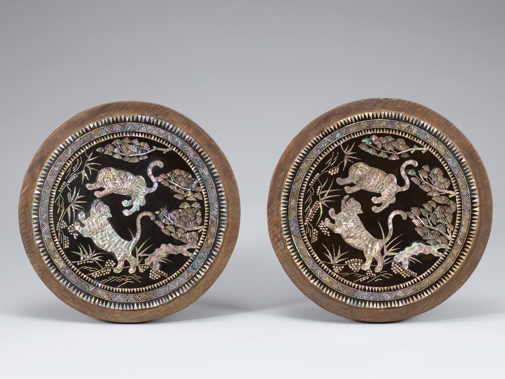 Pair of round lacquer pillow-end panels inlaid with mother-of-pearl tigers, pine and bamboo
